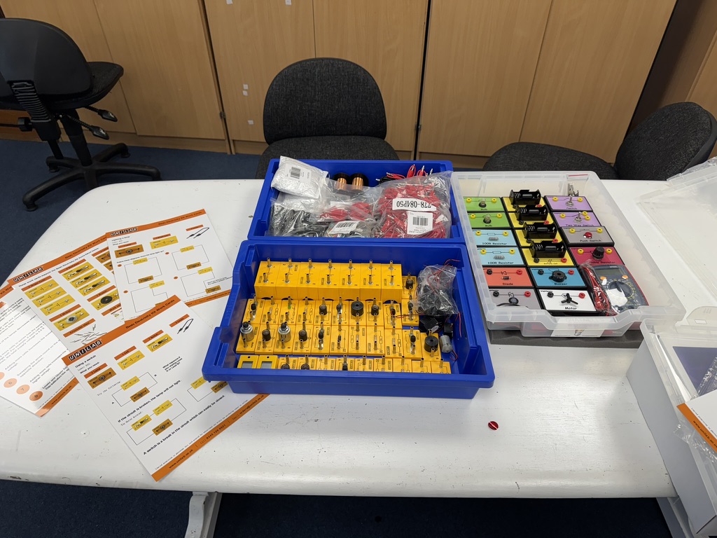 Electricity lesson kits with circuit boards, components and printed activity guides laid out for teachers