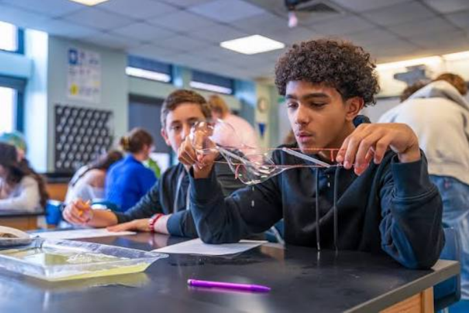 A pupil stretching a sheet of home-made slime between his hands during a polymers lesson